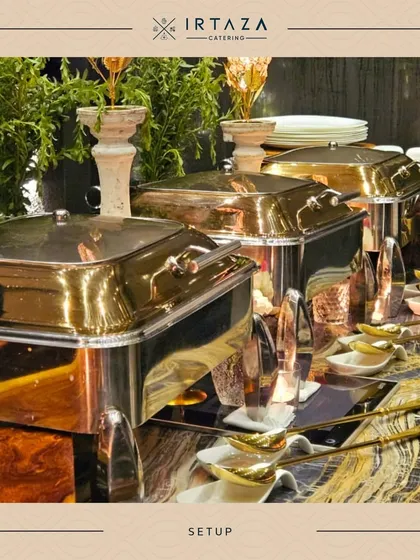 A luxurious buffet arrangement featuring a mix of gold and silver chafing dishes against a backdrop of lush greenery. The combination of metallic tones adds a layer of sophisticated richness to the display.