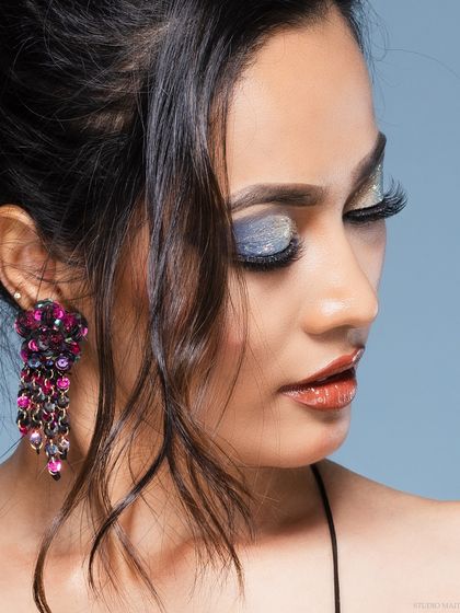 A profile beauty shot, focusing on the model's earring and shimmery eyeshadow.