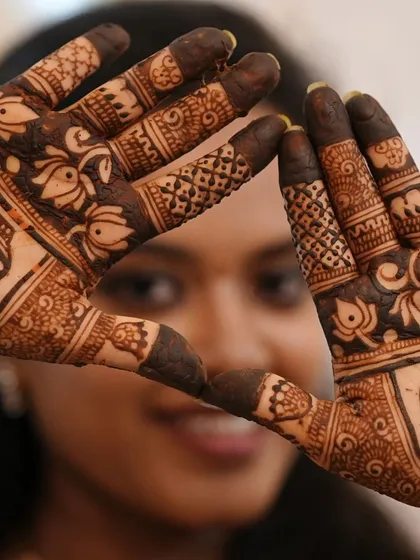 A creative shot of a bride making a heart shape with her hands, with the focus on the intricate details of the henna.
