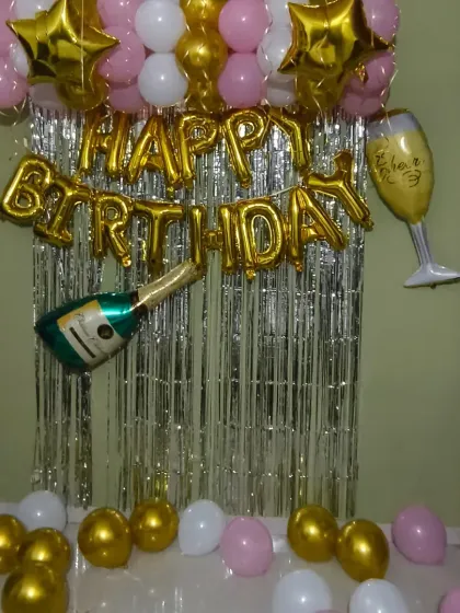 A classic gold, pink, and white home birthday decoration. This budget-friendly option includes a shimmer curtain, foil balloons, and a champagne bottle prop for a fun, celebratory touch.