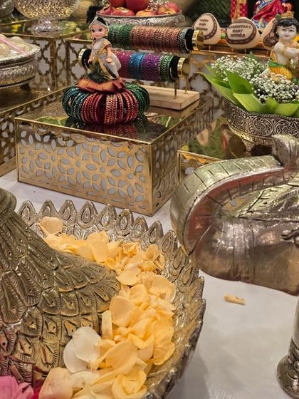 A close-up of silver peacock and elephant props used to hold flower petals and other offerings.