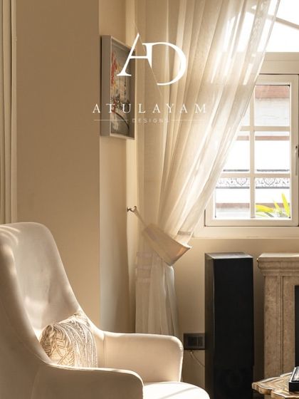 A sunlit corner with a vintage-style white armchair next to a classic fireplace, creating a perfect, serene reading nook.