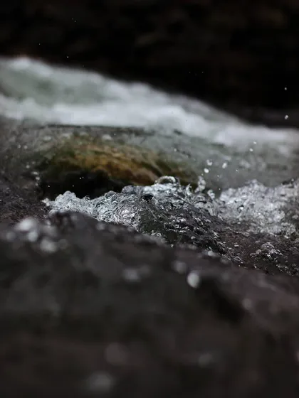 A close up shot of water flowing over rocks. The camera freezes the motion of the bubbles and splashes, reminding me that time, like water in a river, is always flowing away.