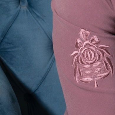 A macro shot of the intricate Resham silk embroidery on the sleeve of our pink Prince Coat. This floral motif is hand-stitched, showcasing our dedication to fine craftsmanship.