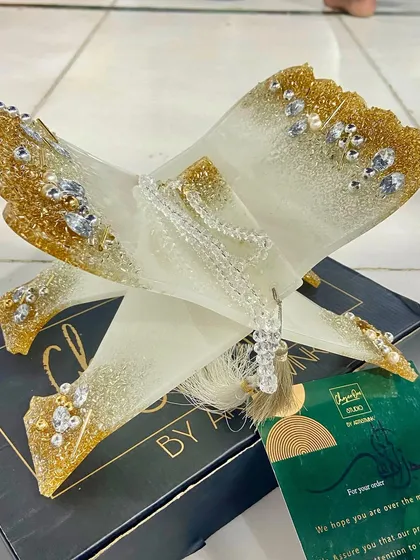 A classic white and gold Quran holder, complete with a matching bookmark and crystal tasbeeh. This piece is shown with its elegant packaging, making it a perfect ready-to-give gift.