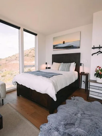 This bedroom is a perfect retreat, with large windows offering beautiful views and a simple, elegant design. The use of natural textures and a neutral color palette creates a restful environment.
