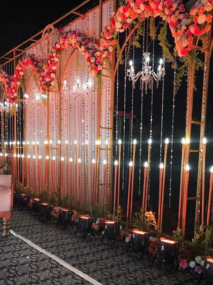 A closer look at the reception stage details. You can see the intricate floral work on the arches and the warm glow from the rows of candle-like lights, creating a deeply romantic ambiance.