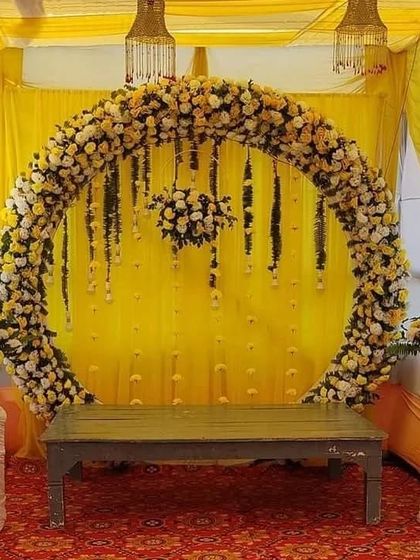 A circular floral arch made of yellow and white flowers, creating a beautiful backdrop for a Haldi or Mehendi ceremony.