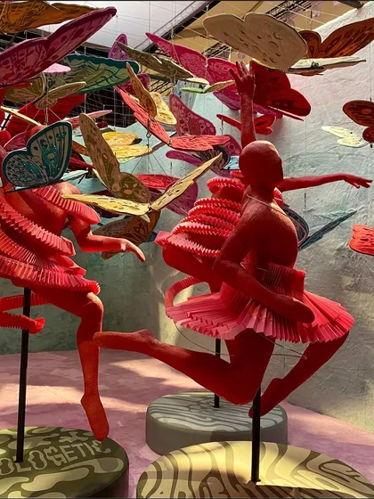 Our work often explores bold ideas through dynamic forms. This piece, part of the 'We/Us' trend, features vibrant red figures in expressive dance poses, surrounded by a cloud of butterflies. The use of folded paper and sculptural forms creates a liberated and adventurous energy, challenging traditional notions of space.