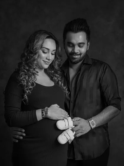 A sweet black and white photo of the couple holding a pair of baby shoes, symbolizing the new life they are waiting for.