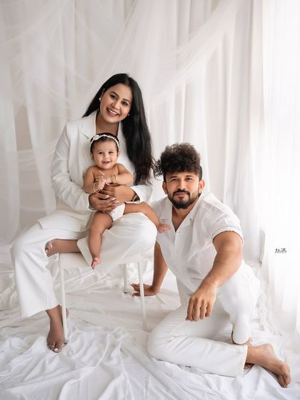 A stylish family portrait in all-white outfits against a clean, white backdrop.