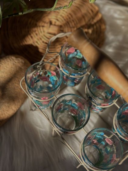 A top-down view of the peacock tea glasses in their metal carrier, highlighting the intricate details on each glass.