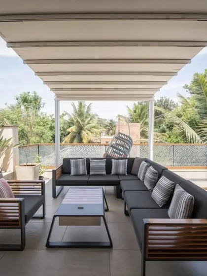 This large, covered terrace is perfect for family gatherings. The expansive L-shaped sofa provides ample seating, while the overhead canopy offers shade, creating a perfect outdoor living room.