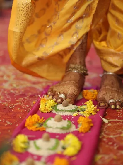 A beautiful moment from a wedding ceremony, capturing the bride's feet adorned with intricate mehendi as she participates in the rituals.