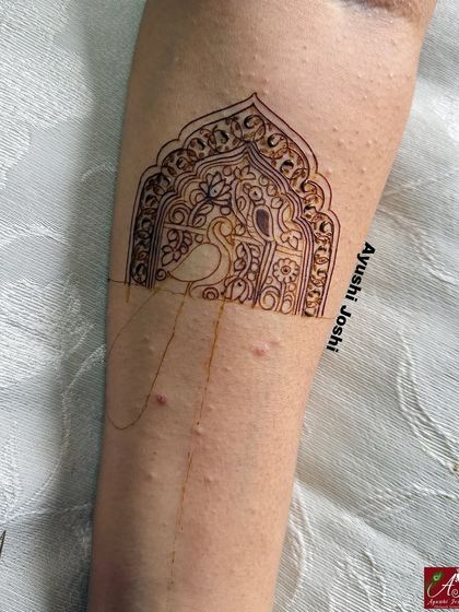 An outline of a peacock within an ornate arch for a baby shower mehendi. This shows the initial sketch for a design that combines both divine and decorative elements.
