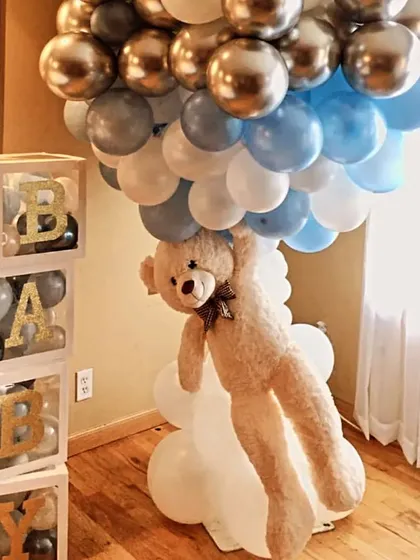 Our teddy bear theme is all about cuddly cuteness. Here, a fluffy teddy bear appears to be floating up with a column of balloons, next to custom "BABY" blocks filled with smaller balloons.