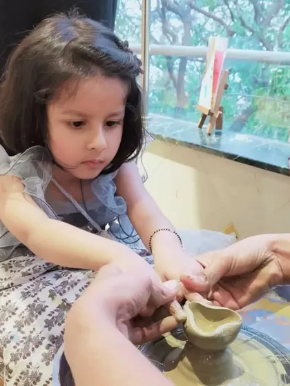 A parent and child work together to shape a small diya on the wheel. This is a perfect example of our parent-toddler bonding sessions, combining culture and creativity.