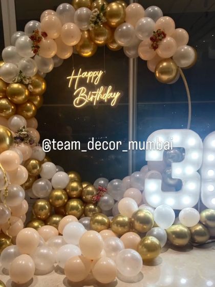 A close-up of the elegant 30th birthday balloon arch in peach, white, and gold, perfectly framing the neon sign.