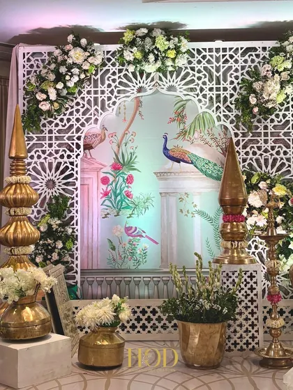 Blending art with tradition is one of my passions. For this wedding stage, I incorporated a beautiful hand-painted Pichwai art backdrop featuring majestic peacocks, framed by intricate white latticework and traditional brass decor for a culturally rich feel.