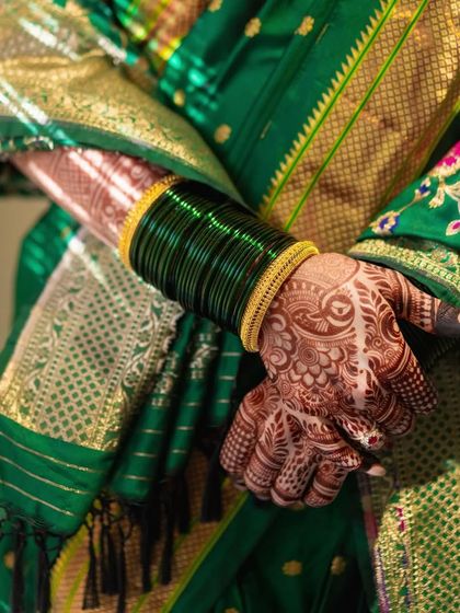 The traditional 'Hirva Chuda' or green bangles, an essential part of a Marathi bride's attire. Paired with her henna-stained hands, it's a beautiful symbol of her new journey.