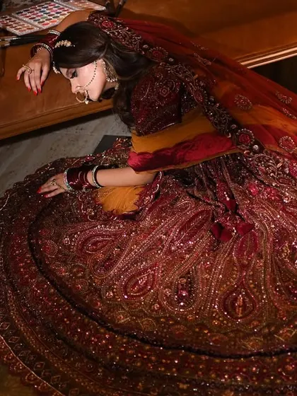 An artistic, top-down shot that emphasizes the incredible spread and detail of the lehenga skirt. This unconventional angle creates a visually interesting composition that is sure to stop the scroll.