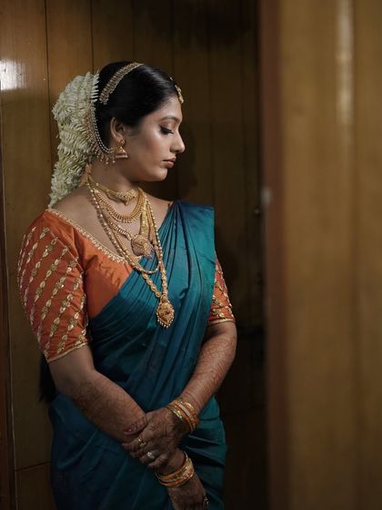 A side profile showcasing the traditional hairstyle with a jasmine garland and the subtle contouring of the makeup. Every angle is considered to ensure a picture-perfect result.