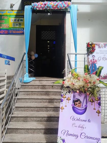 An entrance decoration for a baby's naming ceremony, with a welcome board and fresh flower arrangements.