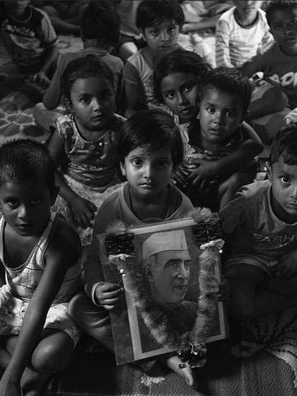 Children at a learning centre, one holding a portrait of Jawaharlal Nehru. This image from the exhibition highlights the intersection of education, childhood, and the broader socio-economic challenges in affected regions.