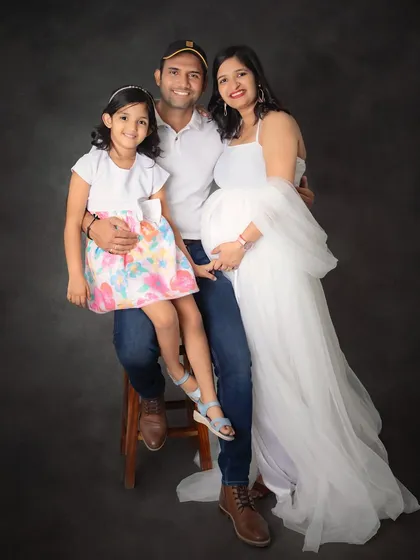 A classic family portrait celebrating the upcoming arrival. The mom-to-be looks radiant in a white gown, surrounded by her loving family in our studio.