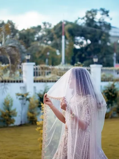 A mysterious and elegant shot of the bride-to-be with her veil, captured in a beautiful garden setting during her engagement shoot.