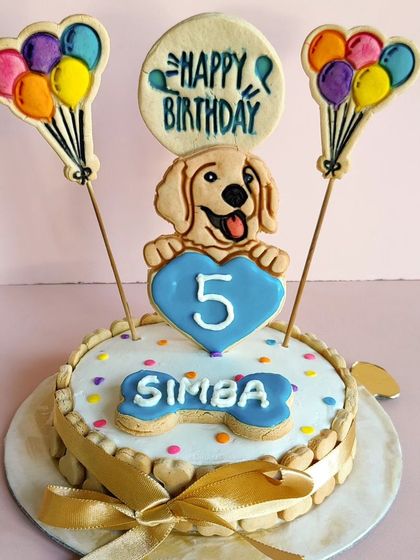 Simba's 5th birthday cake, up close. The cake is lined with bone-shaped biscuits and tied with a ribbon, making it look like a special gift.