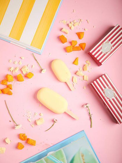 Our mango ice cream bars, a sweet and fruity frozen fix, surrounded by pieces of fresh mango.