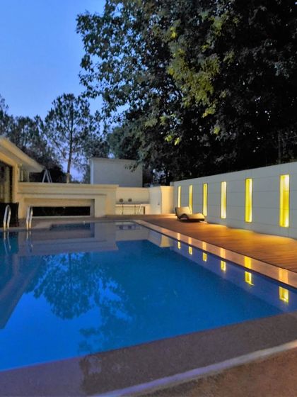 Another view of the expansive swimming pool, showing the wooden deck and the simple, elegant lines of the boundary wall that ensures privacy without feeling enclosed.