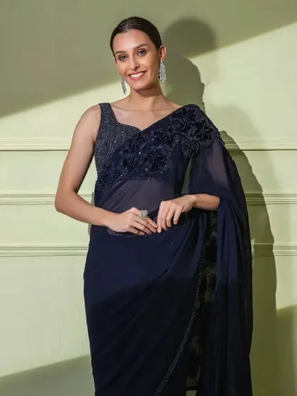 A smiling model wearing the classic navy georgette saree with tonal floral embroidery. A perfect example of understated elegance.