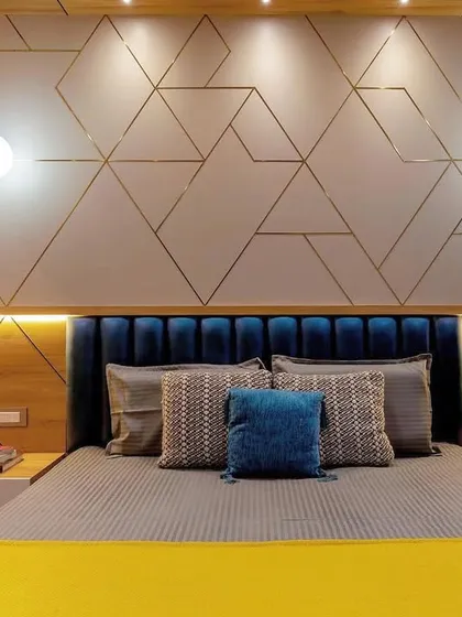 This bedroom features a striking geometric pattern on the wall behind the bed, created with metallic inlays. The deep teal velvet headboard and pops of yellow create a bold, contemporary look.