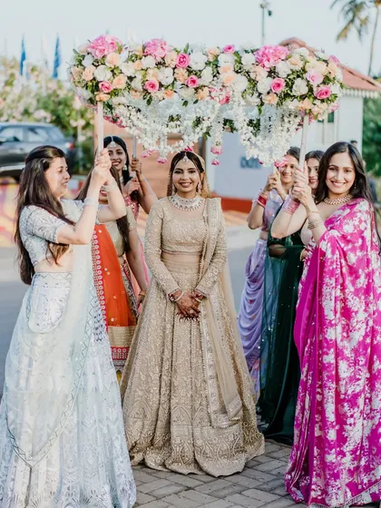 The bride's grand entrance under a floral canopy. Her golden look is absolutely breathtaking, making her the center of attention.