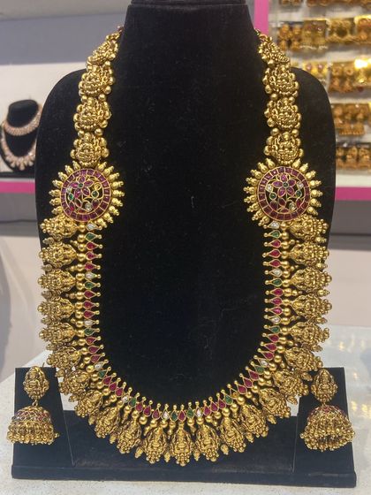 A magnificent temple jewellery haram with ruby and green stone accents. This statement necklace is a centerpiece of our bridal collection.