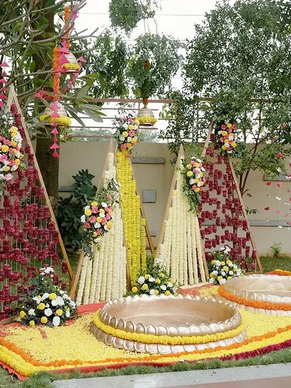 A full view of the vibrant "Phoolon ki Haldi" setup. The triangular backdrops covered in flowers create a unique and modern take on traditional Haldi decor, perfect for a fun, outdoor celebration.