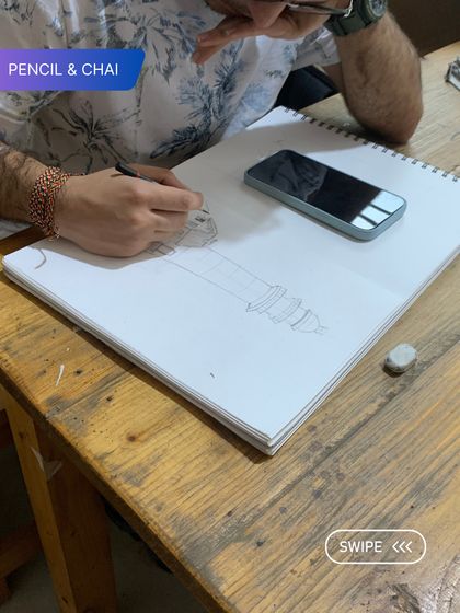 A close-up of a student's hands as he sketches, showing the tools and the process of learning observational drawing.