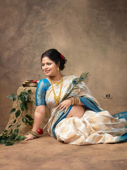 A serene portrait of a mom-to-be in a beautiful silk saree, holding a peacock feather. This pose is rich with cultural symbolism and timeless elegance.