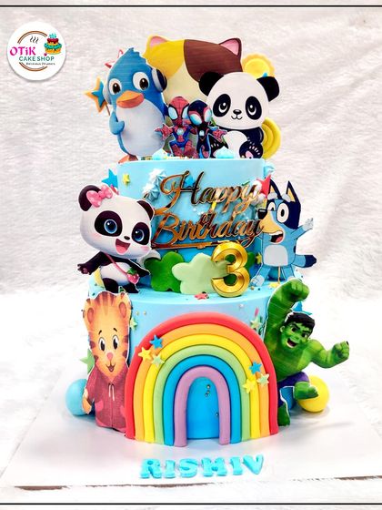 This vibrant, multi-character cake is a child's dream come true. It features characters from different shows, including the Hulk, Bluey, and Baby Panda, all gathered for a third birthday party.