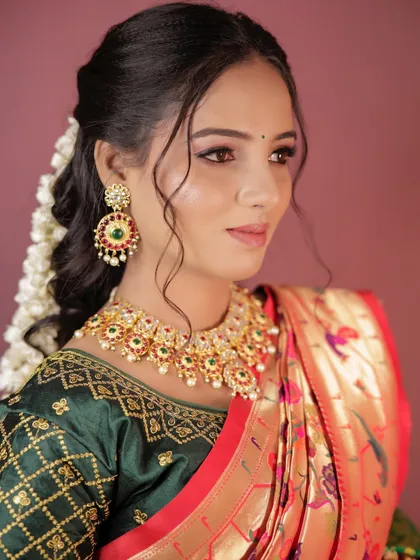 The side profile highlights the traditional hairstyle with a gajra and the intricate earring design.