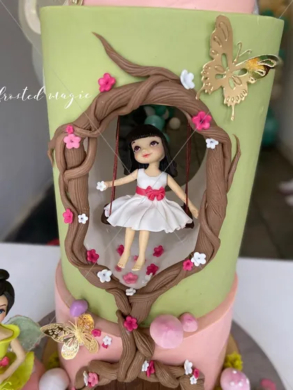 The magic is in the details. This little girl on a swing, part of a larger fairy-themed cake, was sculpted entirely by hand to bring a touch of enchantment to a first birthday celebration.