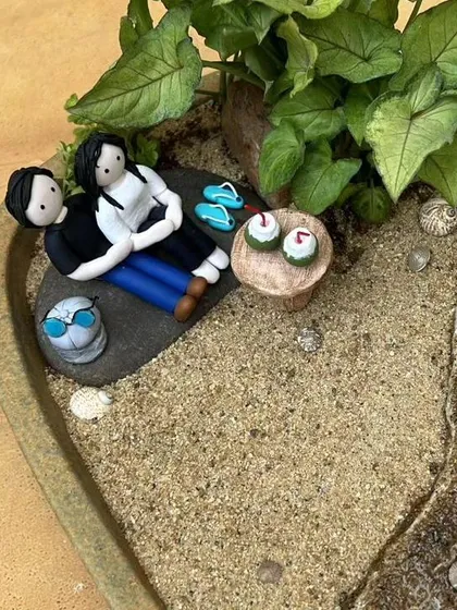 A close-up of the couple figurines, relaxing on the sand with their miniature accessories. Every detail is personalized.