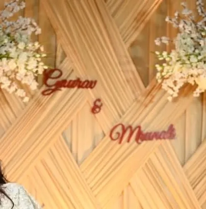 A custom laser-cut sign with the couple's names, Gaurav and Manali, placed on a textured backdrop. This is a wonderful way to personalize a stage or photo booth.