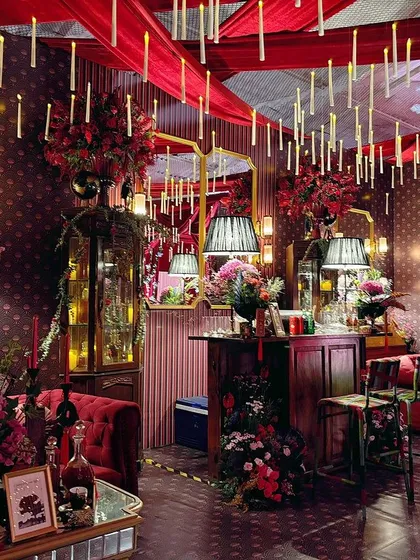 The full view of the Japanese-inspired red glam lounge, with floating candles, custom furniture, and dramatic red draping creating a moody and sophisticated atmosphere.
