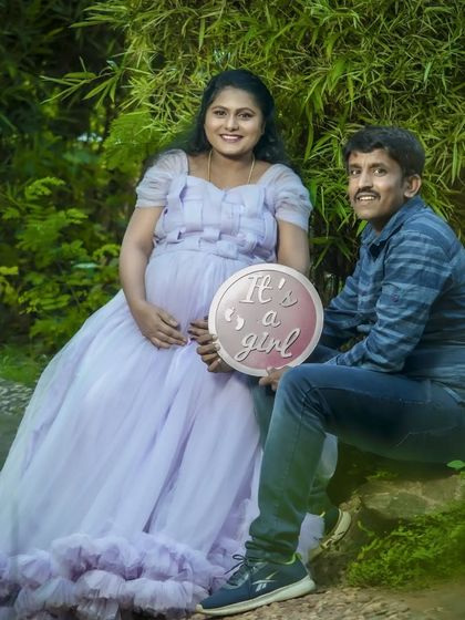 A happy gender reveal moment in a beautiful garden. The couple holds an "It's a girl" sign, sharing their joy in a serene, natural setting.