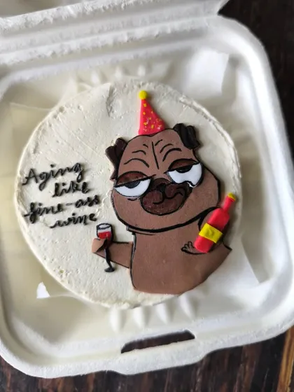 Celebrate a birthday with a sense of humor. This quirky bento cake features a hand-drawn pug character with the message "Aging like fine-ass wine," showing how I can tailor designs to be fun and personal.