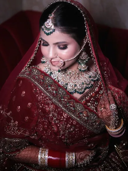 A quiet moment before the ceremony. This bride looks serene and beautiful with her deep red velvet lehenga, showcasing the detailed eye makeup and perfectly blended skin finish.