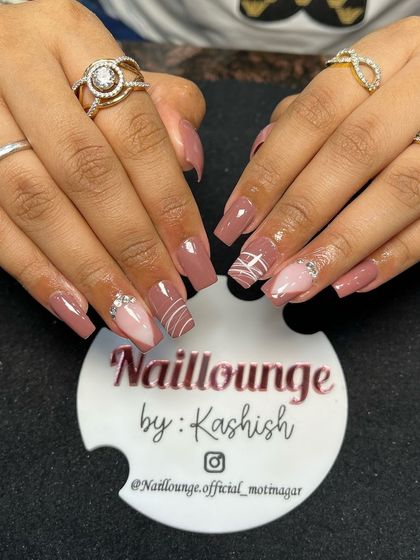A sophisticated nude set with abstract white lines and a sparkling pink glitter accent nail.